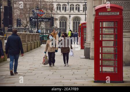 Menschen mit schützenden Gesichtsmasken gehen während der Coronavirus-Pandemie auf dem Parliament Square entlang der Straße. London, Großbritannien, Februar 2021. Stockfoto