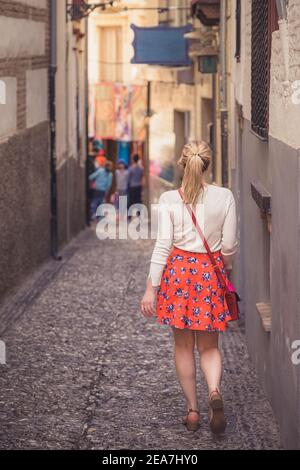 Eine junge blonde Touristin erkundet die malerischen und engen Gassen der Altstadt (Albaicin oder arabisches Viertel) Granada, Spanien, Andalusien. Stockfoto