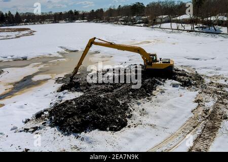 Reinigung der Boden des Sees ein Baggereimer ist Im Winter im Wasserbagger einweichen Stockfoto
