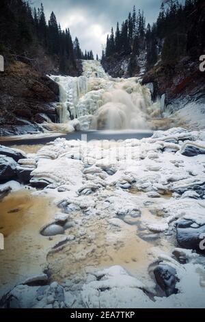 Gefrorener Wasserfall im norwegischen Wald. Homla Fluss in Norwegen. Kaltes, frostiges Winterwetter. Schnee und Eis im Wald. Mettifossen Wasserfall. Stockfoto