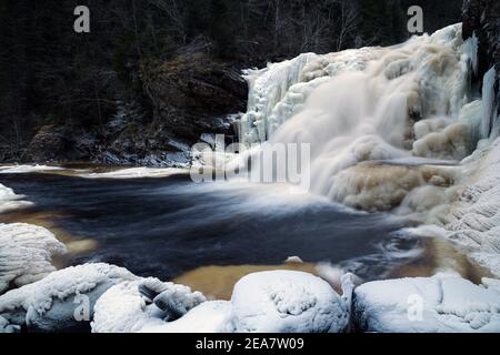 Gefrorener Wasserfall im norwegischen Wald. Homla Fluss in Norwegen. Kaltes, frostiges Winterwetter. Schnee und Eis im Wald. Mettifossen Wasserfall. Stockfoto