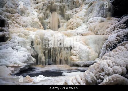 Gefrorener Wasserfall im norwegischen Wald. Homla Fluss in Norwegen. Kaltes, frostiges Winterwetter. Schnee und Eis im Wald. Dolandfossen Wasserfall. Stockfoto