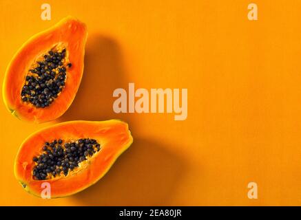 Papaya Frucht auf orange Farbe Hintergrund. Kreatives Food-Konzept mit Sonnenschatten Stockfoto