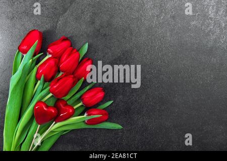 Rote Herzen Tulpenblüten auf dunklem Hintergrund. Dekoration zum Valentinstag Stockfoto