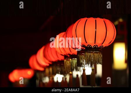 Rote chinesische Laternen leuchten in einer Reihe auf einer Nachtstraße. Neujahrsfest in Asien Stockfoto