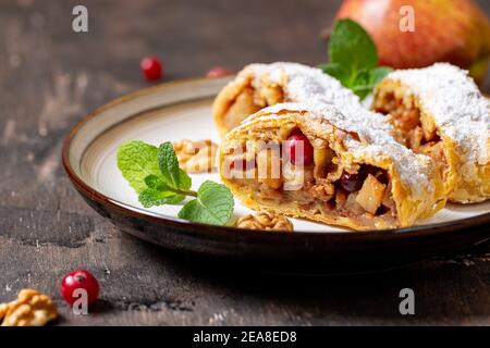 Hausgemachter duftender Strudel mit Äpfeln und Zimt auf einem Teller auf einem hölzernen Hintergrund mit Platz für Text, Stockfoto