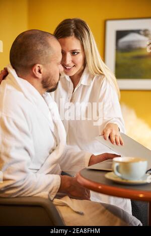 Junge Frau sucht ihren beschäftigten Ehemann Aufmerksamkeit Stockfoto