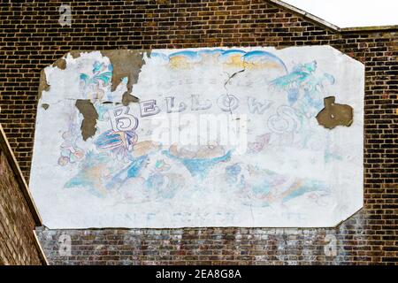 Ein altes verblassenes Schild, das Bellows Patisserie und Brasserie am Giebel-Ende eines Backsteingebäudes in Highgate Village, North London, Großbritannien, anwirbt Stockfoto