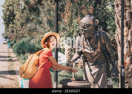 04. September 2020, Türkei, Antalya: Eine glückliche Frau wäscht sich in Form einer Wasserträgerskulptur die Hände auf der Straße in einem Springbrunnen. Stockfoto