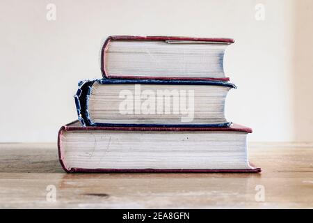 Ein Stapel von drei alten Hardback-Nachschlagewerken auf einem Alter Holzschreibtisch Stockfoto