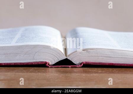 Nahaufnahme eines offenen Hardback-Nachschlagebuchs auf einem alten Holztisch Stockfoto