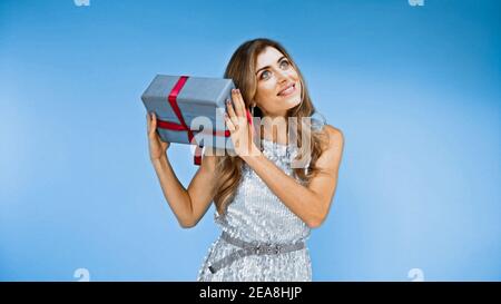 Glückliche Frau hält verpackte Geschenkbox auf blau Stockfoto