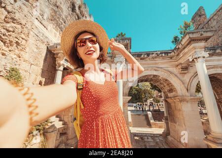 Glückliche weibliche Touristen macht Selfie-Fotos vor der Kulisse des Hadrianstors - eine beliebte Attraktion in der Altstadt von Antalya, Türkei Stockfoto