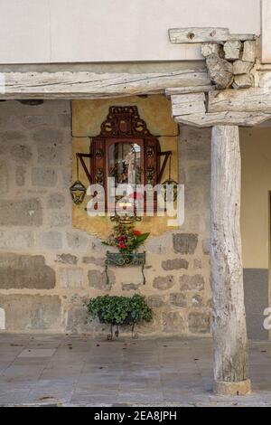 Detail einer religiösen Nische und Blumentopf in der Wand unter der mittelalterlichen Arkade in der Altstadt von Ampudia, Provinz Palencia, Castilla y Leon, Spanien Stockfoto