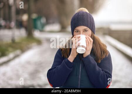 Glückliche Brünette Frau mittleren Alters gehen für einen Spaziergang und trinken Ein Kaffee zum gehen Stockfoto
