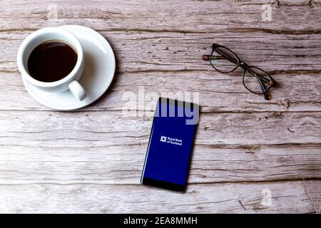 Ein Handy oder Handy auf einem Holz gelegt Tabelle mit der Royal Bank of Scotland App als nächstes öffnen Zu einem Kaffee Stockfoto
