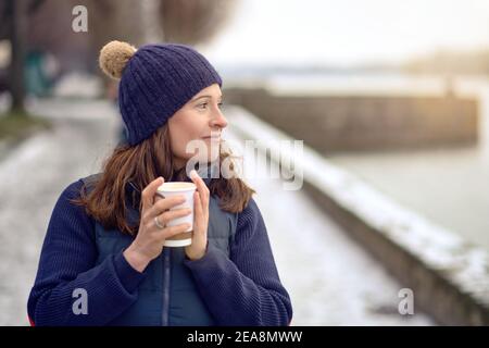 Glückliche Brünette Frau mittleren Alters gehen für einen Spaziergang und trinken Ein Kaffee zum gehen Stockfoto