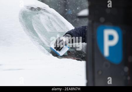 08. Februar 2021, Nordrhein-Westfalen, Bielefeld: Ein Fahrer räumt auf einem Parkplatz seiner Windschutzscheibe Eis und Schnee. Nach dem schweren Wintereinbruch kommt die große Kälte nach Nordrhein-Westfalen. Nach der Prognose des Deutschen Wetterdienstes vom 08,02.2021 werden die Temperaturen unter der Woche, auch tagsüber, nicht über Null Grad steigen. Foto: Friso Gentsch/dpa Stockfoto