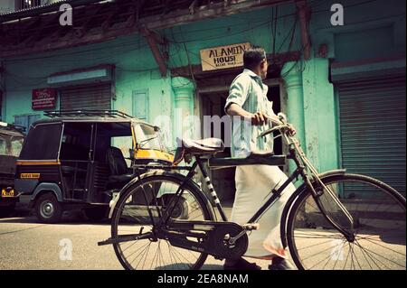 Mann mit Fahrrad vorbei Tuk Tuk Taxi, Fort Cochin, Kerala, Indien Stockfoto