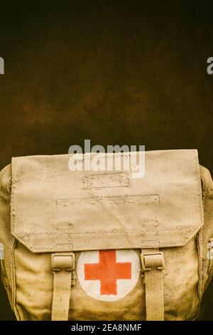 Retro-Stil Bild eines Vintage Jute erste-Hilfe-Armee Tasche vor einem alten braunen verwitterten Hintergrund Stockfoto