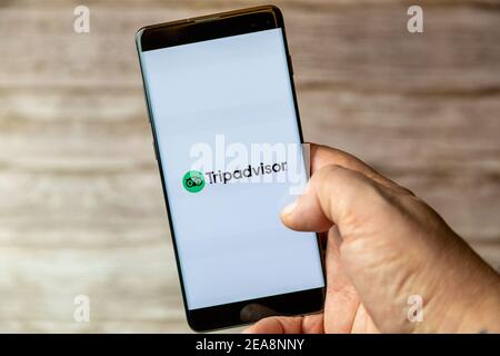 Ein Mobiltelefon oder Mobiltelefon, das in einem gehalten wird Hand mit der Tripadvisor-App auf dem Bildschirm geöffnet Stockfoto