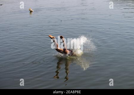 Der Mensch taucht von einer Klippe und Kopf-zuerst in den Ozean Stockfoto