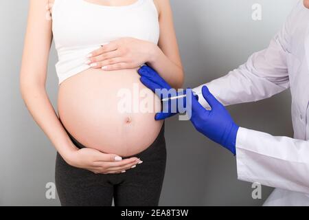 Konzept der Neugeborenen-Familie. Eine schwangere Frau mit der Hand eines Arztes zu impfen, Krankenschwester impfen junge Mädchen mit einem Kind oder jungen Entwicklung in th Stockfoto