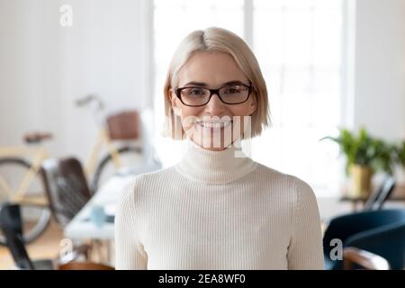 Kopfaufnahme des glücklichen professionellen Angestellten, der im modernen Büro posiert Stockfoto