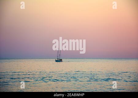 Yacht segelt gegen Sonnenuntergang maritime Abendspaziergang. Romantischer Ausflug auf Luxusjacht während des Sonnenuntergangs am Meer. Stockfoto