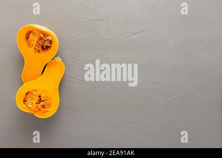 Roher Bio-Butternut-Kürbis oder Gramma in halber Nahaufnahme auf grauem Beton-Hintergrund geschnitten, Draufsicht, kopieren Spase Stockfoto