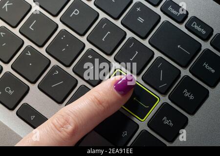 Nahaufnahme des weiblichen Fingers durch Drücken der ENTER-Taste auf der Laptop-Tastatur. Stockfoto
