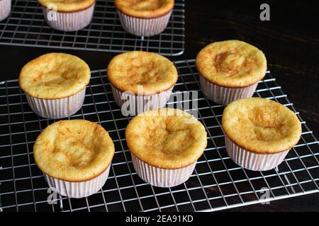 Vanilla Cupcakes auf einem Wire Cooling Rack: Warme gelbe Cupcakes kühlen vor dem Hinzufügen von Vereisung Stockfoto