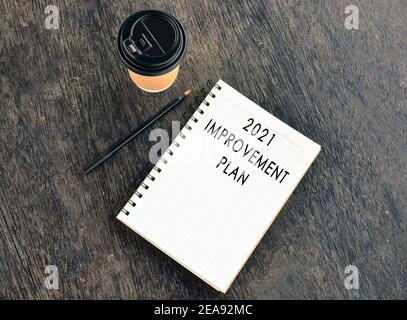 Text auf Notizblock mit Einweg-Kaffeetasse und Stift auf Holztisch Stockfoto