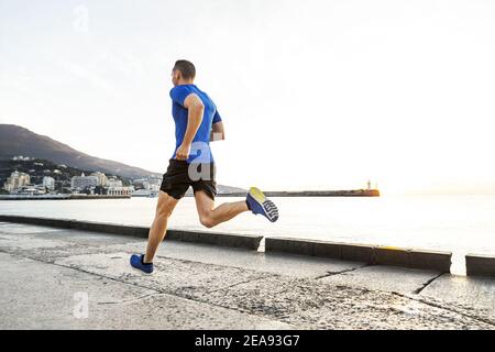 Mann Läufer laufen am Morgen entlang der Uferpromenade in der Stadt Stockfoto