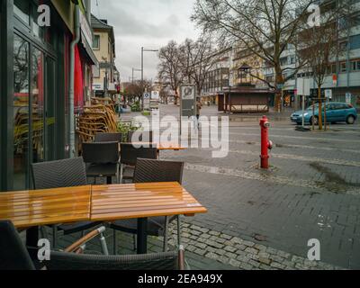 Neuwied, Deutschland - 06. Februar 2021: Leere Straßen und gestapelte Stühle vor einer Kneipe an einem regnerischen Tag in der zweiten Sperre auf Basis der Corona-Pfanne Stockfoto