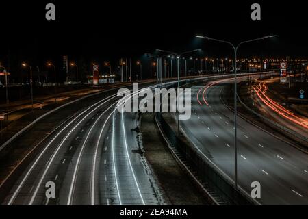 Geschwindigkeitsverkehr bei dramatischer Sundown-Zeit - leichte Wege auf Autobahn Autobahn Autobahn in der Nacht, Langzeitbelichtung abstrakter städtischer Hintergrund. Stockfoto