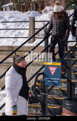 Ottawa, Ontario, Kanada - 6. Februar 2021: Ein Schild auf einer Treppe, die zum Rideau Canal Skateway führt, informiert die Besucher, entgegenkommenden Menschenhändlern nachzugeben Stockfoto