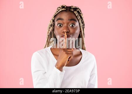 Schwarze Frau, die Finger auf die Lippen stampft und ein Zeichen für die Stille macht Stockfoto