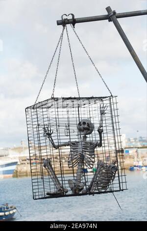 Ein künstliches Skelett aus Käfig mit Blick auf den inneren Hafen von Brixham. Brixham verfügt über eine große Fischereiflotte, ist bei Touristen beliebt und ist Gastgeber für ein p Stockfoto