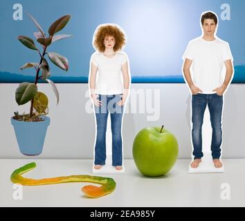 Collage, Mann und Frau, in Jeans und T-Shirt, mit grünem Apfel und Gummischlange, neben Gummibaum, voe weiß-blauer Hintergrund, symbolisches Bild Stockfoto