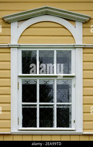 Rechteckiges Fenster mit weißem Rahmen und Visier auf dem Hintergrund einer Holzwand aus gelben Brettern. Aus den Fenstern der Welt-Serie. Stockfoto