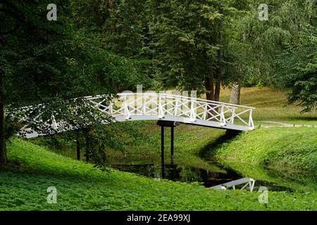 Weiß gewölbte Fußgängerbrücke über einen Teich im Park. Stockfoto