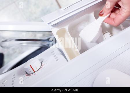 Laden Sie das Waschpulver aus nächster Nähe in die Waschmaschine. Stockfoto