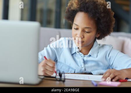 Mehr Zeit für Kunst. Gemischtes Rennen Teenager Schulmädchen Zeichnung auf Papier mit bunten Markern während des Studiums mit Laptop zu Hause während der Quarantäne Stockfoto