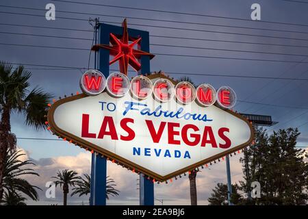 Blick in die Abenddämmerung auf das berühmte Welcome to Fabulous Las Vegas Schild mit Palmen und Dachgitter im Hintergrund. Stockfoto