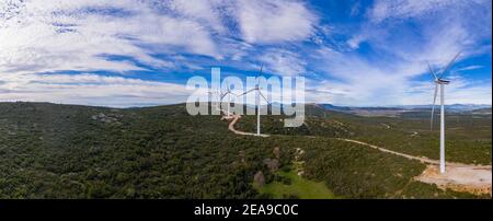 Windparkpanorama. Windturbinen und kurvige Straße auf dem Hügel, Luftdrohne Ansicht. Grüne ökologische Energieerzeugung. Alternative Energieanlage, b Stockfoto