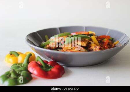 Tawa gebratener Paneer und gebratene Paprika. Eine leckere Kombination als Vorspeise. Fotografiert in einer blumenförmigen Schale auf weißem Hintergrund. Stockfoto