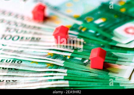 100 Euro Rechnungen und Miniaturhäuser, Konzept der Kosten für den Kauf eines Hauses. Stockfoto