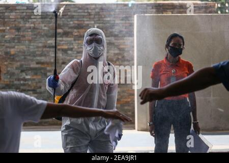 Ein Arbeiter desinfiziert einen Mann, der mitten in der Coronavirus-Pandemie in Pasig City, Metro Manila, Philippinen, das Rathaus betritt. Stockfoto