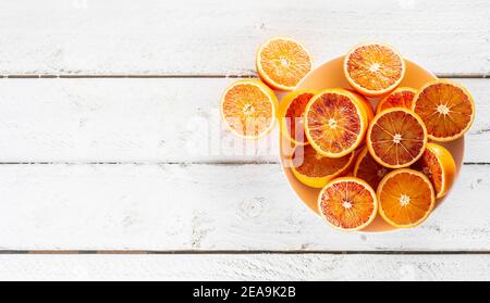 Blutorangen in Scheiben geschnitten auf einem Teller auf einem weißen Holztisch - von oben gesehen. Stockfoto